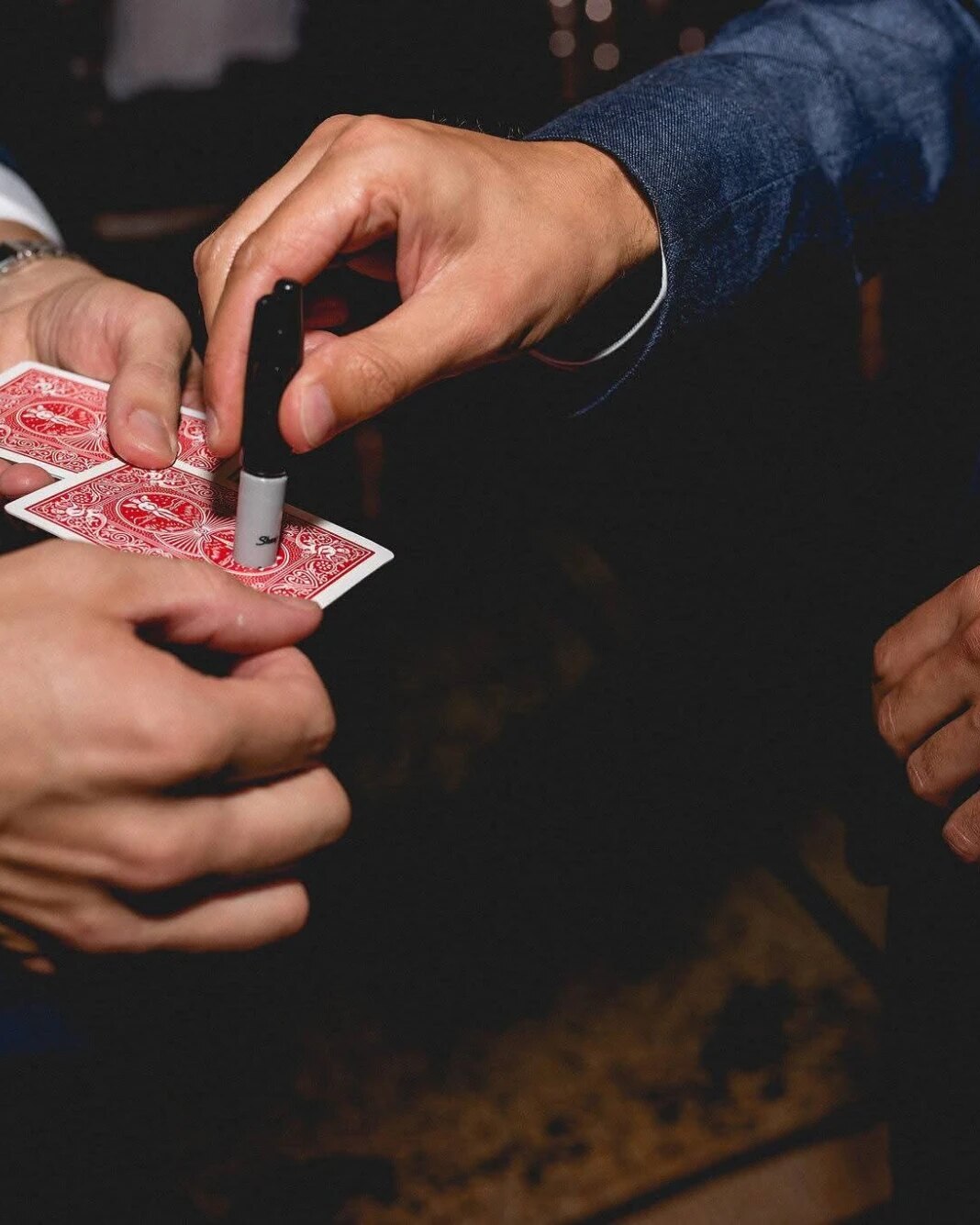 A guest signing a playing card while Neil holds the deck