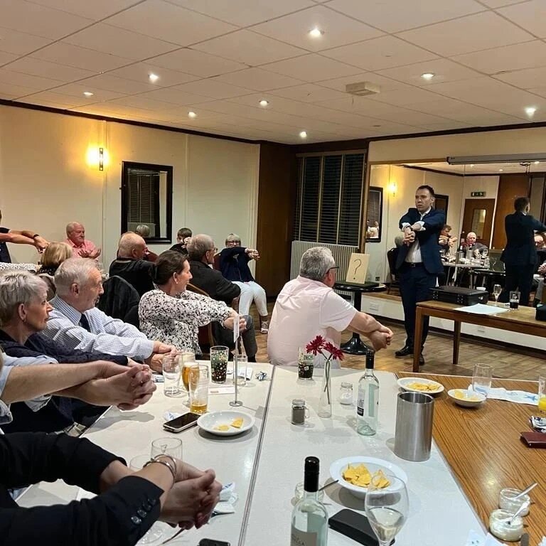 A room of guests watching Neil perform after dinner