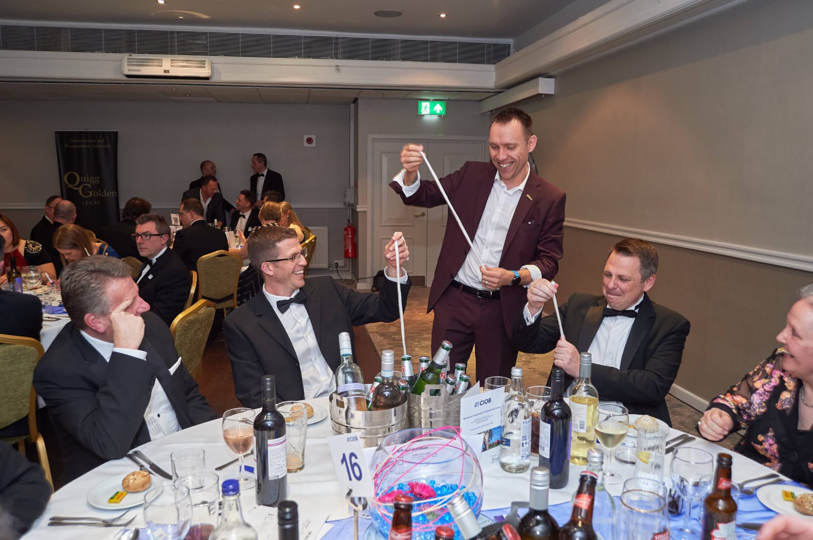 Two dinner guests holding the ends of a rope mid-trick