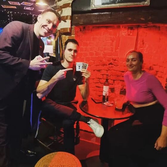 Neil revealing a signed card to two guests in a bar