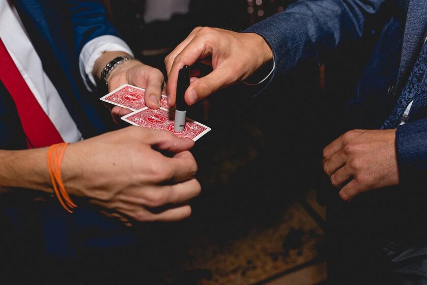 A guest signing a playing card while Neil holds the deck