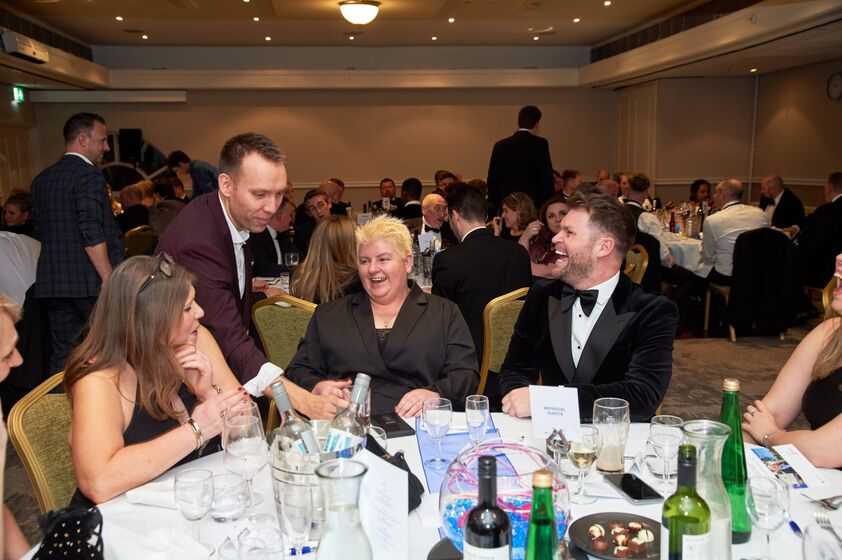A table of guests in black tie laughing during a close-up routine