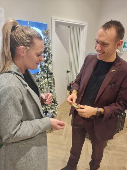 A coin trick for a guest beside a Christmas tree