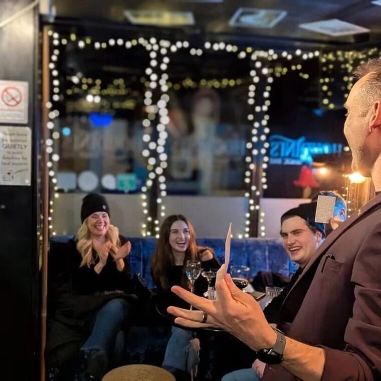 Neil holding a fan of cards at Houdini\'s Magic Bar as the room reacts