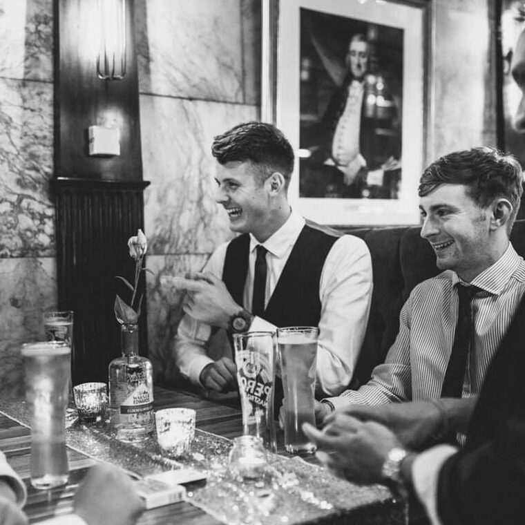 Groomsmen laughing around a table after a card routine